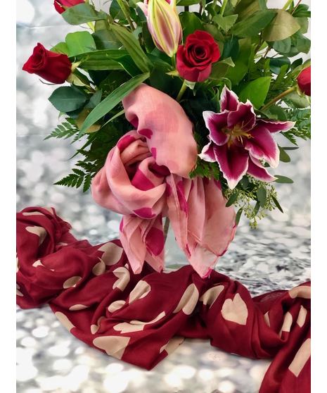 One dozen red roses with lilies and fancy greenery in an elegant, tall vase