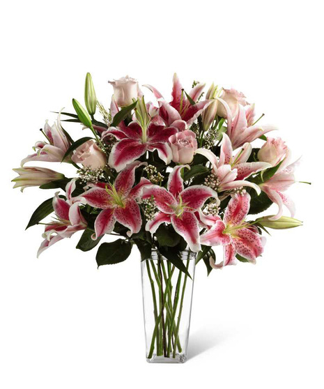 Pink roses, stargazer lilies and greens in a glass vase.