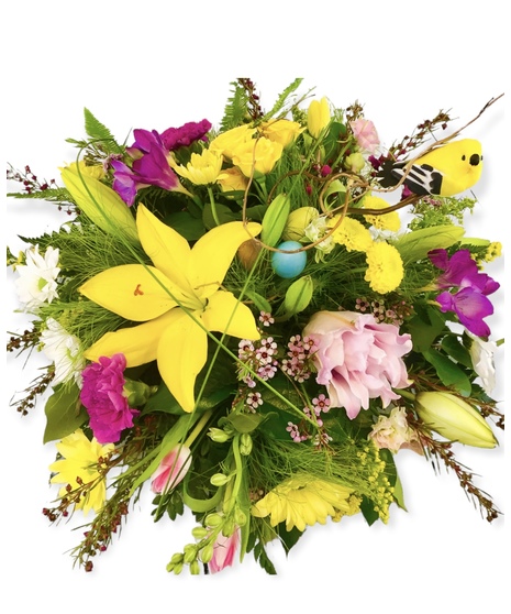 A mix of pink lilies, roses, and carnations in a glass vase decorated with willow branches.