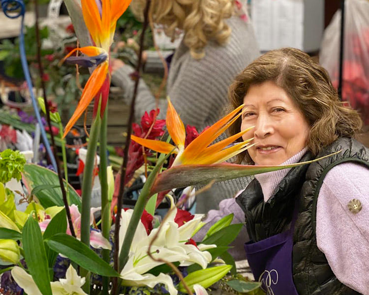 One of our floral designers smiles beside her latest creation